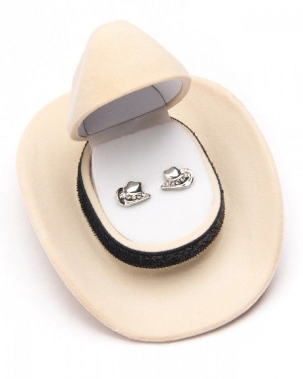Mira estos pendientes en forma de sombrero cowboy plateados con pequeños cristales brillantes presentados en un estuche en forma de sombrero western.